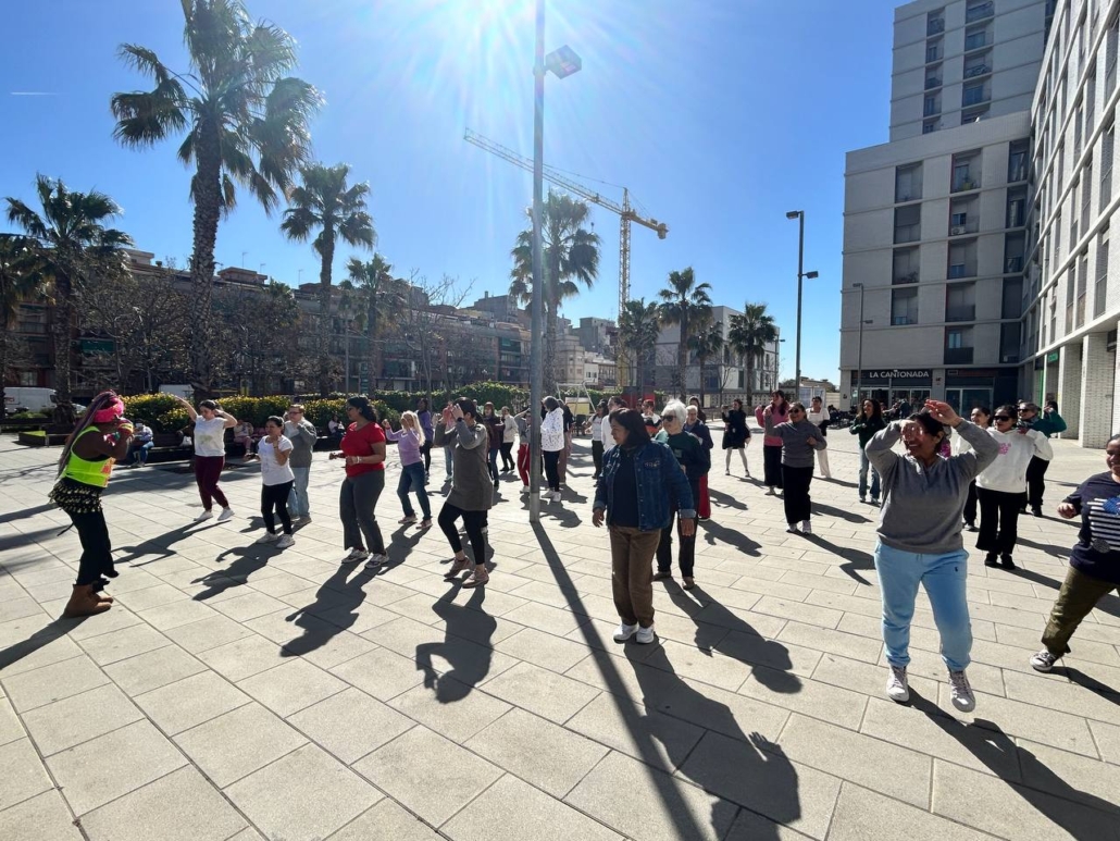 Un grup de quaranta dones ballen en una plaça a l'aire lliure. 