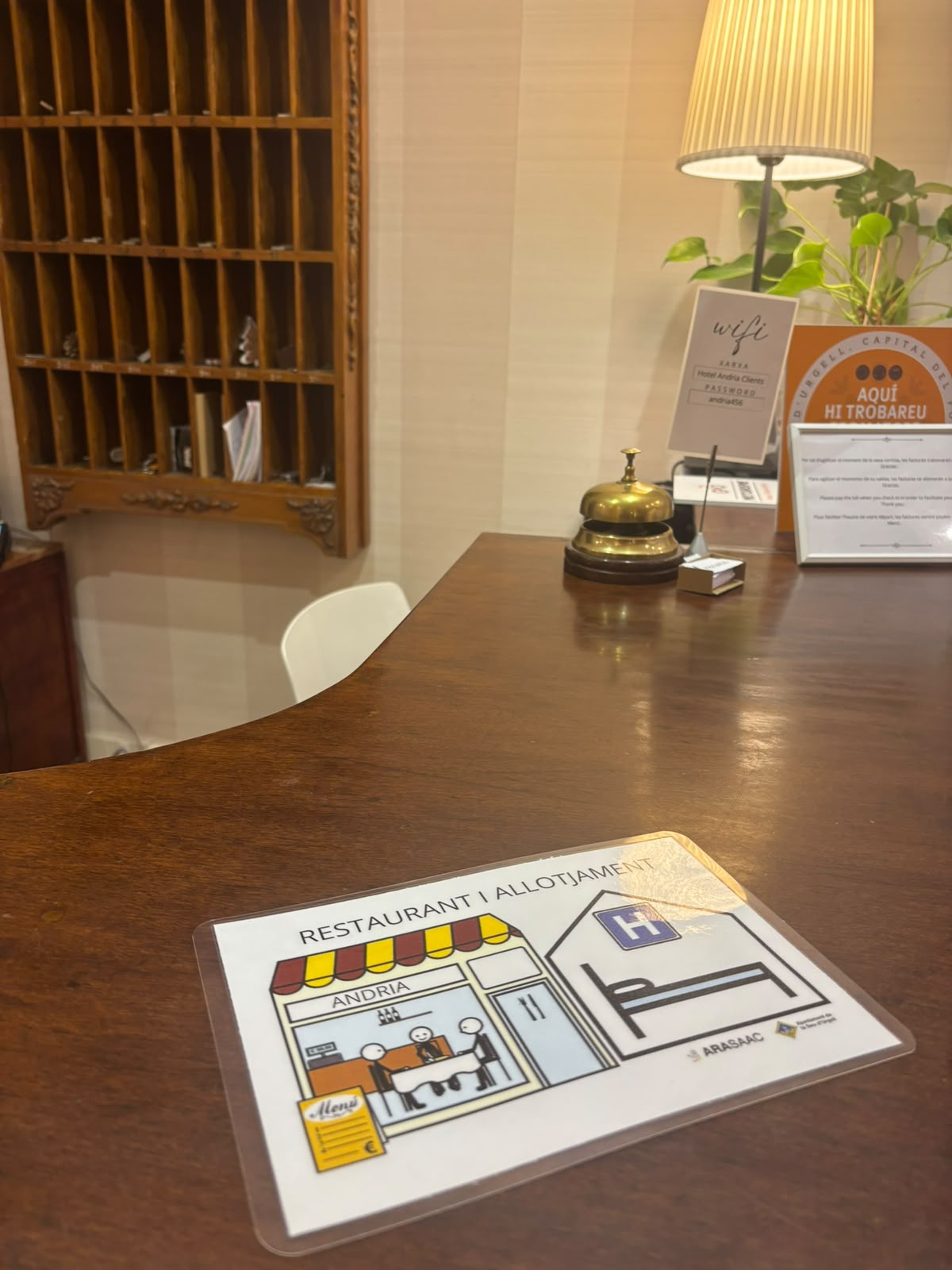 Imatge d'un pictograma sobre comerç i hosteleria. Està situat a sobre del taulell d'un hotel. 