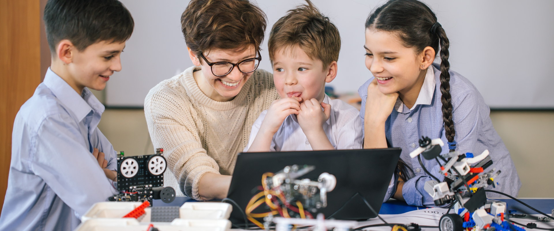 Tres infants aprenent tecnologia amb una dona