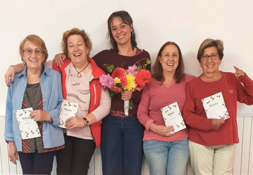 Participants del taller Verd Digital del Punt Òmnia Itinerant del Pallars Sobirà somrient mentre mostren el recull de remeis amb plantes elaborat col·lectivament.