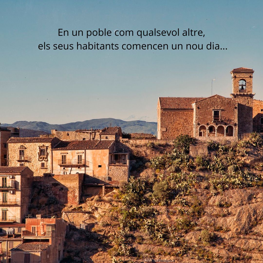 Vista d’un poble de muntanya amb cases de pedra i teulades antigues, envoltat de vegetació i cactus, amb una església de campanar visible a la dreta. Al cel clar, es llegeix el text: “En un poble com qualsevol altre, els seus habitants comencen un nou dia…”. Al fons es veuen muntanyes.