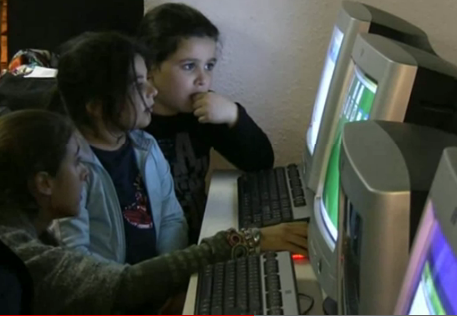 Imatge d'infants durant el taller d'Arromi davant l'ordinador amb una monitora