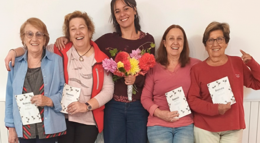 Participants del taller Verd Digital del Punt Òmnia Itinerant del Pallars Sobirà somrient mentre mostren el recull de remeis amb plantes elaborat col·lectivament.