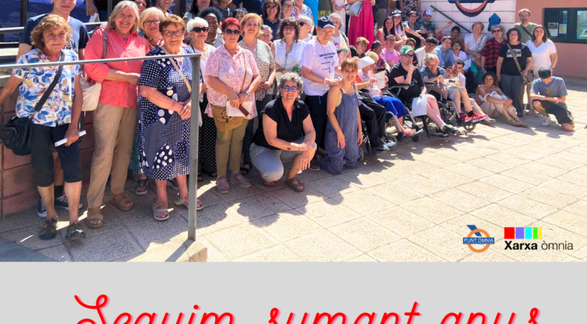 Imatge de l'acte de lliurament de persones participant del punt Òmnia. Apareix un grup nombrós de persones a unes escales amb el logo d'Òmnia de fons. 