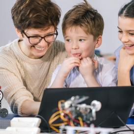 Tres infants aprenent tecnologia amb una dona