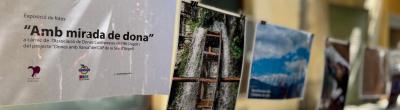 Imatge de l'exposició "Amb mirada de dona". Apareix un cartell amb el nom de l'exposició imprès i es veuen de fons algunes de les fotografies seleccionades.